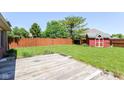 Spacious backyard featuring a well-maintained lawn, wood fence, and a charming red storage shed at 3126 Oakmont Dr, Lapel, IN 46051