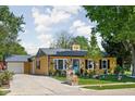 Quaint yellow home with blue door, flowers, detached garage and a paved driveway at 3433 Brewer Dr, Indianapolis, IN 46222