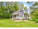 A gray home featuring a covered porch and a back deck nestled among green trees at 42 E Brookville Rd, Fountaintown, IN 46130