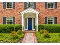 Classic brick home featuring a blue front door, white portico, and manicured landscaping at 5356 S U.S. Highway 421, Zionsville, IN 46077