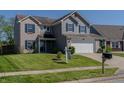 Two-story home with brick, vinyl siding, a 'For Sale' sign, well-maintained lawn and manicured landscaping at 6491 Enclave Blvd, Greenwood, IN 46143