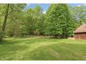 Expansive backyard with lush green grass, trees, and partial view of the home's exterior at 7730 Bear Creek Rd, Morgantown, IN 46160