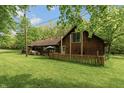 Cabin exterior highlighting the spacious yard, wood siding, and a charming picket fence at 7730 Bear Creek Rd, Morgantown, IN 46160