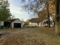 Spacious backyard with a detached garage and a car parked on the leaf-covered lawn under mature trees at 8345 N State Road 109, Wilkinson, IN 46186