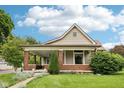 Charming exterior featuring a covered porch with brick columns and a beautifully landscaped front yard at 910 E Pike St, Martinsville, IN 46151