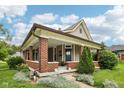 Inviting home with a covered porch with brick pillars, detailed trim, and professionally landscaped front yard at 910 E Pike St, Martinsville, IN 46151