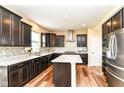 Well-equipped kitchen with dark cabinets, granite countertops, stainless steel appliances, and an island at 9860 Gallop Ln, Fishers, IN 46040