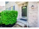 Close-up of the front door with decorative details, surrounded by manicured bushes and exterior lighting at 10075 Niagara Dr, Fishers, IN 46037
