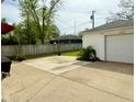 Spacious concrete patio area next to a detached garage and partially fenced yard at 106 S Denny St, Indianapolis, IN 46201