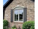 A close up of an exterior window with grey shutters accenting the multi-colored brick facade and trimmed window at 1102 Redwood Dr, Brownsburg, IN 46112