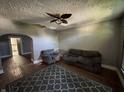 Living room with dark gray walls, plush seating, patterned rug, and a ceiling fan, ready for renovation at 1314 Laurel St, Indianapolis, IN 46203