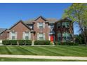 A two-story brick home with shutters, a red front door, and a manicured lawn at 2219 Stone Manor Ct, Avon, IN 46123
