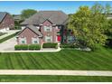 Charming two-story brick home with manicured lawn, mature tree, and inviting red front door at 2219 Stone Manor Ct, Avon, IN 46123