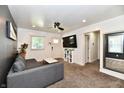 Inviting living room with gray sofa, television, ceiling fan, and white door to the outside at 3021 Eastern Ave, Indianapolis, IN 46218