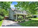 Well-maintained home featuring a covered porch, lush greenery, and a driveway leading to the rear of the property at 4527 Central Ave, Indianapolis, IN 46205