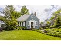 Charming blue home with well-manicured lawn, trimmed bushes, and a quaint front entrance and white trim windows at 5219 N New Jersey St, Indianapolis, IN 46220
