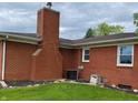 Rear exterior view with chimney, showing brick siding, roof, and small garden area at 5457 W 900 North, McCordsville, IN 46055