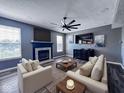 Modern living room with fireplace, contemporary furniture, large windows, and sleek ceiling fan at 6155 W Bayfront, McCordsville, IN 46055
