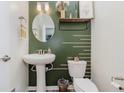Stylish half bath features decorative green walls, a pedestal sink, and modern fixtures at 6460 Wasco Dr, Whitestown, IN 46075
