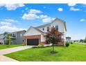 Beautiful two-story home boasting a well-maintained lawn, brick accents, and a tree-lined yard on a bright, sunny day at 6843 Black Cherry Ter, Brownsburg, IN 46112