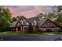 Stately Tudor-style house with brick and timber accents, lush landscaping, and driveway at 7406 N Washington Blvd, Indianapolis, IN 46240