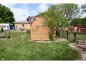 Backyard shed with double doors and a well-maintained lawn in a fenced yard at 76 Manhattan Ave, Indianapolis, IN 46241