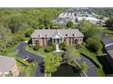 Aerial view of stately brick building with mature trees, parking, and a pond at 8751 Jaffa Court East Dr # Apt 32, Indianapolis, IN 46260