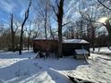 Backyard covered in snow features a small structure with a snow-covered roof, and bare trees against a partly cloudy sky at 8803 S Sleepy Hollow Rd, Waldron, IN 46182