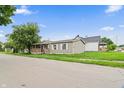 Charming one-story home with a covered porch and mature tree, complemented by the surrounding greenery and blue sky at 1000 E Willard St, Muncie, IN 47302