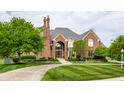 Stunning red brick home with a well-maintained lawn and a circular driveway at 10554 Hyde Park, Carmel, IN 46032