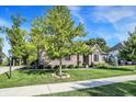 Classic brick home with a beautifully landscaped front yard featuring a mature tree and manicured lawn at 16890 Catkins Ct, Westfield, IN 46074