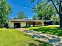 Inviting single-story home with a spacious front yard, driveway, and mature trees surrounding the property at 4457 Campbell Ave, Indianapolis, IN 46226