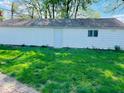 Spacious backyard with lush green grass and a detached garage in the background at 4850 E University Ave, Indianapolis, IN 46201