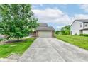 Exterior view of the house showing the concrete driveway, green lawn, and landscaping at 5372 Bay Harbor Dr, Indianapolis, IN 46254