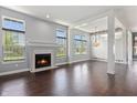 Spacious living room featuring a fireplace, large windows, dark hardwood floors, and elegant lighting at 6897 Abercon Trl, Noblesville, IN 46062