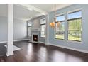 Bright living room boasts a cozy fireplace, dark hardwood floors, and an elegant chandelier, perfect for entertaining at 6897 Abercon Trl, Noblesville, IN 46062