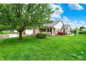 Beautifully landscaped front yard with mature trees and a well-maintained lawn leading up to a brick-and-vinyl home at 7840 Park Ward Pl, Indianapolis, IN 46259
