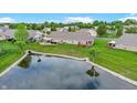 Aerial view of a home with a pond, surrounded by lush greenery and neighboring houses at 7937 Bentley Commons Dr, Indianapolis, IN 46259