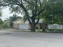 A street view of a charming tan brick ranch home with a two car garage and neighborhood signage at 8417 S Sherman Dr, Indianapolis, IN 46237