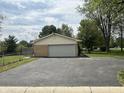 Tan brick ranch style home with an attached two car garage and an asphalt driveway at 8417 S Sherman Dr, Indianapolis, IN 46237