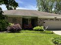 Charming ranch home featuring a well-manicured lawn, brick facade and an attached two car garage at 9521 Gemini Dr, Indianapolis, IN 46229