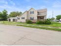 View of a two-story home with tan siding, dark shutters, a front porch and a three-car garage at 1225 S Monroe St, Muncie, IN 47302