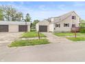 View of a two-story home with tan siding and three garages with dark brown doors at 1225 S Monroe St, Muncie, IN 47302