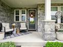 Cozy front porch with stone columns, comfortable seating, and a welcoming entrance with decorative wreath at 165 N Bend Dr, Greenwood, IN 46142