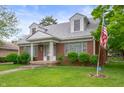 Charming brick home with dormer windows, well-kept lawn, and an American flag at 301 N Kitley Ave, Indianapolis, IN 46219