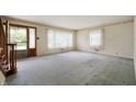 Spacious living room with light blue carpet and multiple windows, featuring a staircase at 301 N Kitley Ave, Indianapolis, IN 46219