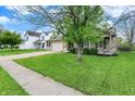 Inviting home with a well-manicured lawn, two-car garage, and mature tree providing shade at 3214 Limber Pine Dr, Whiteland, IN 46184