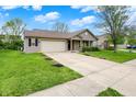 Charming single-story home with two-car garage, well-kept lawn and concrete driveway on a sunny day at 3214 Limber Pine Dr, Whiteland, IN 46184
