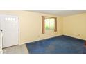 Cozy living room with blue carpeting, a window with curtains, and a door leading to the outside at 3325 Broadview Ct, Indianapolis, IN 46227