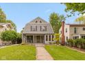 Inviting two-story home showcasing a covered porch, well-manicured lawn, and mature trees under a bright sky at 3614 Guilford Ave, Indianapolis, IN 46205